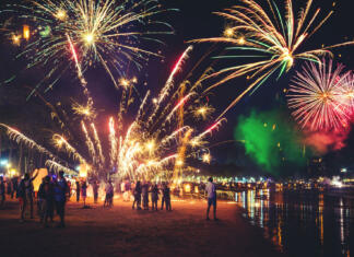 Silvestrovanje v drugih kulturah Fireworks with silhouettes of people in a holiday events.New Year fireworks on the beach. Travelers and people celebrate New year day at Kamala Beach Phuket, Thailand.