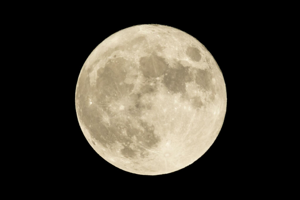 Full moon over the dark black sky at night. High resolution image shot in 2015.