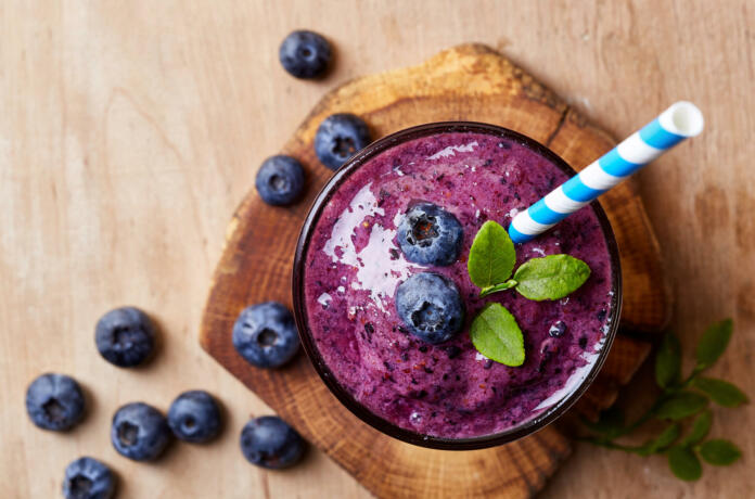 Glass of blueberry smoothie on wooden background from top view