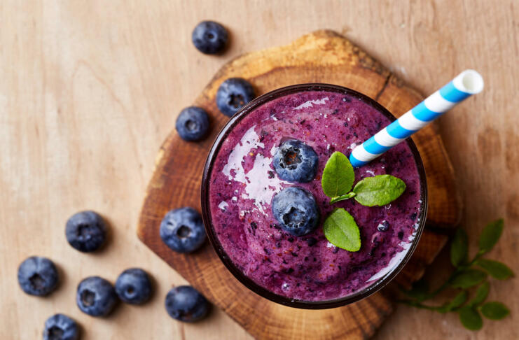 Glass of blueberry smoothie on wooden background from top view