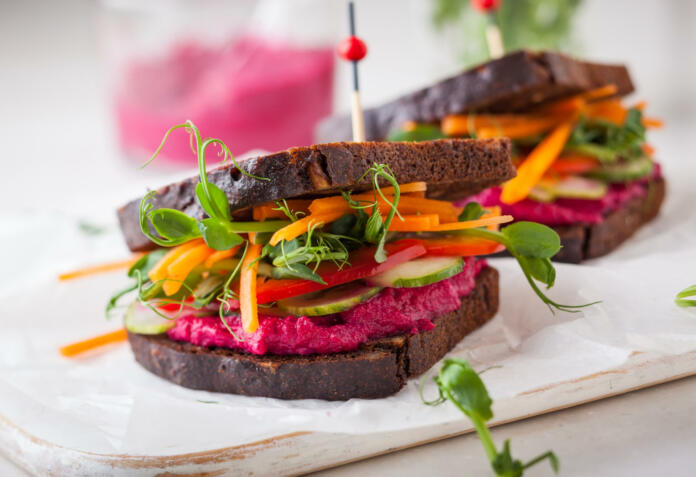 gluten free vegan sandwiches with beet hummus, raw vegetables and sprouts. soft focus