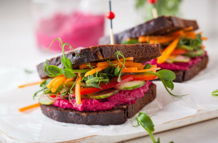 gluten free vegan sandwiches with beet hummus, raw vegetables and sprouts. soft focus
