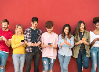 Kaj je s temi milenijci? Group young friends using mobile smartphone outdoor - Millennial generation having fun with new trends social media apps - Youth technology people addicted - Red background