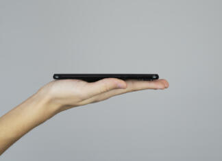 iPhone 14 ima bizarno težavico Hand holding mobile phone side view for presentation, studio shot, template or mockup on a grey background