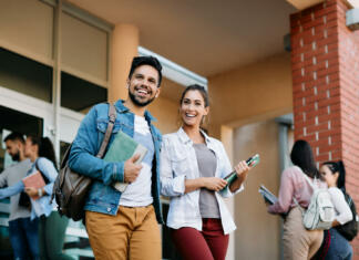 Študentke so v visokošolskih študijih bolj uspešne od študentov Happy university student and his female friend walking after the lecture at campus.