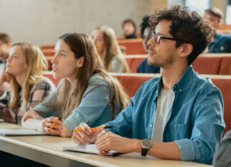 O študiju na FDV iz prve roke In the Classroom Multi Ethnic Students Listening to a Lecturer and Writing in Notebooks. Smart Young People Study at the College.