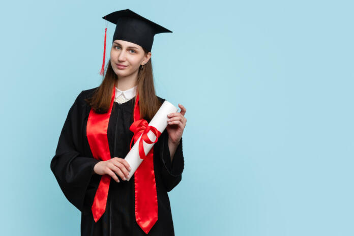 Joy Female Graduate Wearing Ceremony Robe and Graduation Cap Holding Certificate tied with Red Ribbon on Blue Background. Student Girl Celebrating Graduation and Getting Diploma. Degree Paper