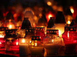 lot of bright, colorful candles standing on graves in the cemetery at night