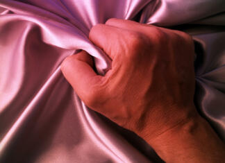 Sedaj bomo lahko tudi moški doživeli ženski orgazem Man grabing satin sheet on the bed.