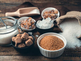 Many different types of sugar on a wooden background. Side view. Culinary background with vintage tinting. The concept of food products.