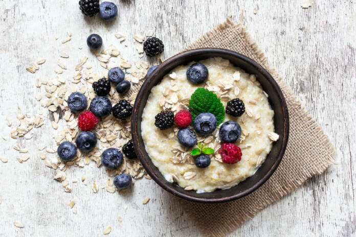 oatmeal porridge with ripe berries - blueberry, raspberry and blackberry for healthy breakfast. flat lay. top view