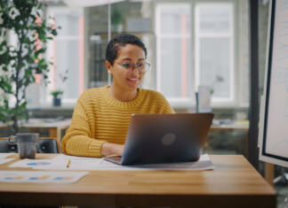 Te zanima pisanje? Iščemo pisce besedil za portal student.si! Portrait of Young Latin Marketing Specialist in Glasses Working on Laptop Computer in Busy Creative Office Environment. Beautiful Diverse Multiethnic Female Project Manager is Browsing Internet.