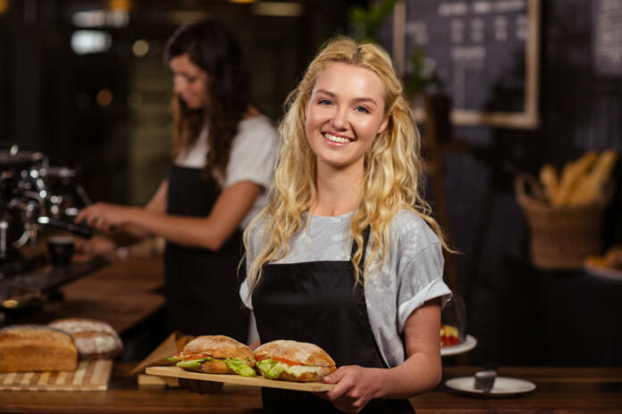 Pretty waitress holding a tray with sandwiches at the coffee shop