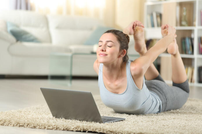 Satisfied woman e-learning yoga exercise using a laptop at home