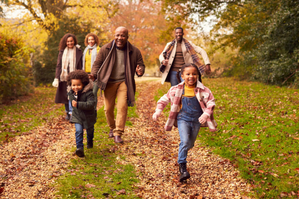 Smiling Multi-Generation Family Having Fun With Children Walking Through Autumn Countryside Together