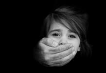 Tudi mladi v boj proti trgovini z ljudmi Strong male hands cover little girl face with emotional stress, pain, afraid, call for help, struggle, terrified expression.Concept Photo of abduction, missing, kidnapped,victim, hostage, abused child