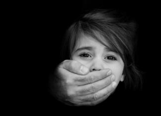 Tudi mladi v boj proti trgovini z ljudmi Strong male hands cover little girl face with emotional stress, pain, afraid, call for help, struggle, terrified expression.Concept Photo of abduction, missing, kidnapped,victim, hostage, abused child