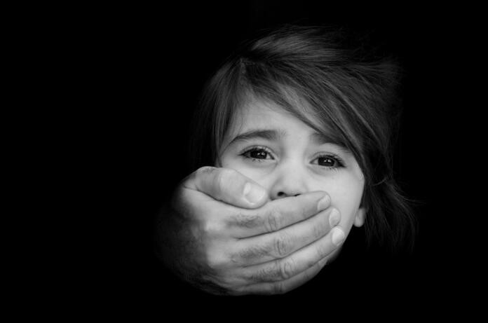 Strong male hands cover little girl face with emotional stress, pain, afraid, call for help, struggle, terrified expression.Concept Photo of abduction, missing, kidnapped,victim, hostage, abused child