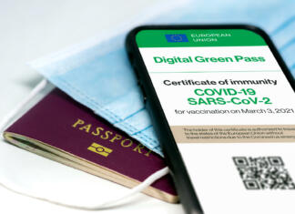 V 7 korakih do digitalnega potrdila in potrdila o cepljenju, prebolelosti ali testiranju The digital green pass of the european union with the QR code on the screen of a mobile phone over a surgical mask and a passport. Immunity from Covid-19. Travel without restrictions.