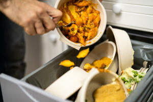 Throwing Away Leftover Food In Trash Or Garbage Dustbin