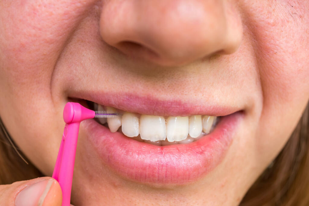 Woman brushing her teeth with interdental brush - dental care concept