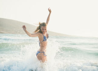 Erotična zgodba: Otok (2.del) Young beautiful blond woman tourist in swimsuit jumping and having fun in wavy waters of Mediterranean sea in Prasonisi cape, Rhodes, Greek summer resort. Travel, vacation, freedom, happiness