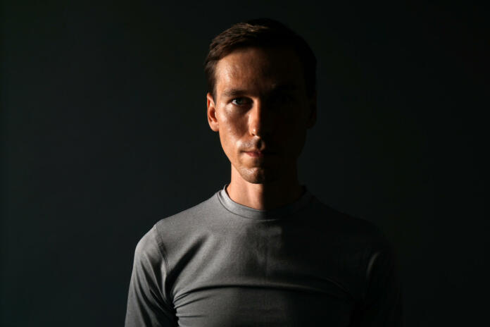 Young caucasian man in t-shirt on gray background.