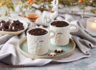 5 načinov uživanja vroče čokolade po svetu Skodelici vroče čokolade, v ozadju so medenjaki in kozarec z rumom