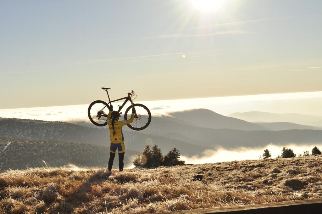 Oseba stoji na vrhu hriba in v rokah drži dvignjeno kolo
