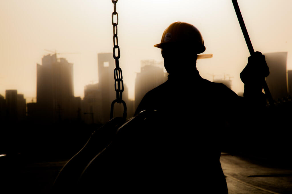 Doha,Qatar - December 11,2017. Construction workers preparing a crane for work in the background skyscrapers in Doha.