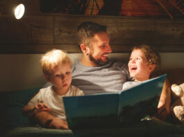 Oče s hčerko in sinom bere pred spanjem