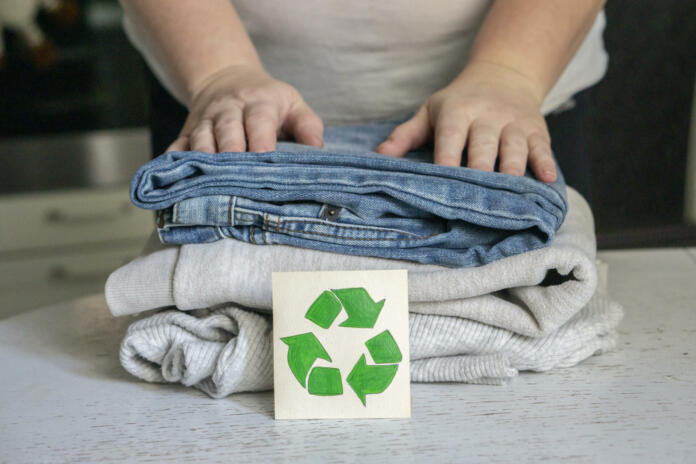 Garment recycling concept. A stack of clothes is on the recycling table. Collection of clothes for recycling.