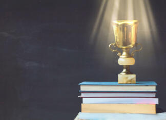 Znani nominiranci za najboljši literarni prvenec 38. Knjižnega sejma! Golden trophy on pile of books, against blackboard, with sun rays over trophy; learning/achievement concept