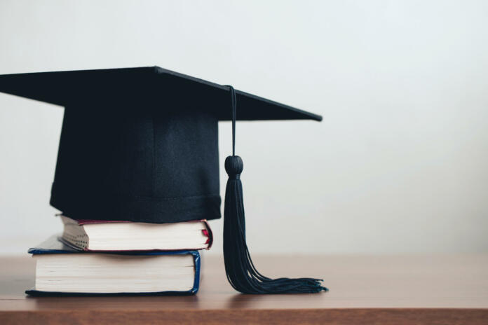 graduation cap on a stack of books with empty space to the right.Graduation concept