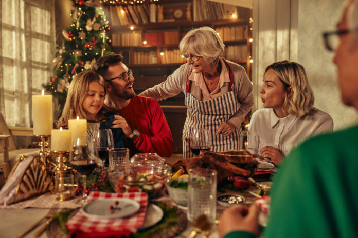 Happy multi-generation family talking while having New Year's meal at dining table.