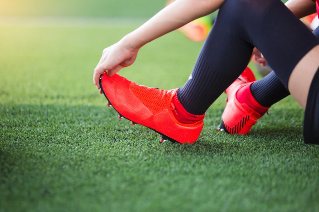 Kid soccer player is sitting and catch the soles of the feet because of pain, soccer player was injured in the foot with pain during competition or practice