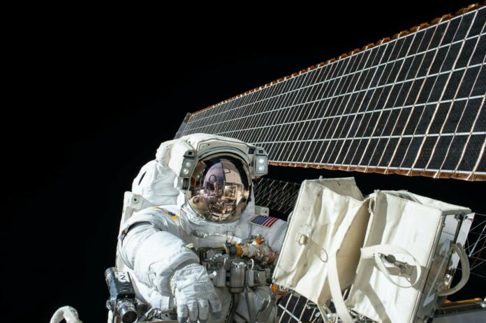 Astronavt v skafandru v vesolju poleg sončnih celic