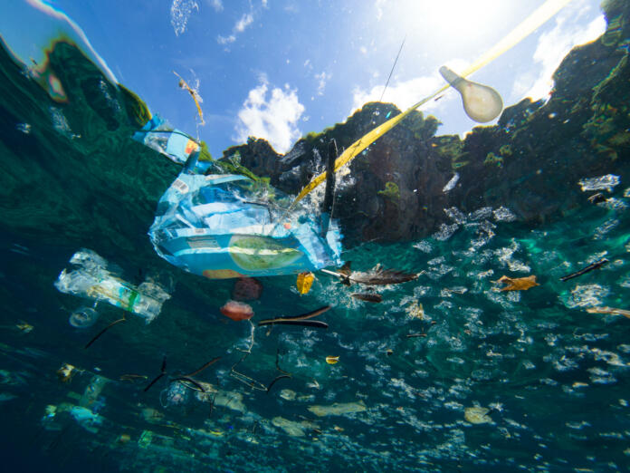 Plastic debris floating on the ocean surface, shot underwater.