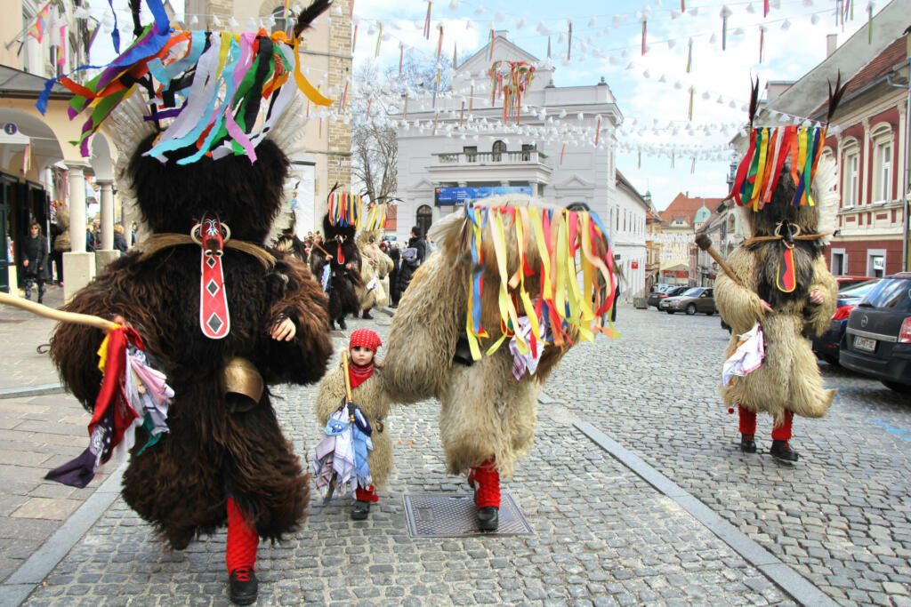 Ptuj, Slovenia - March 1, 2014: A Group of Kurents, in the famous traditional masks, dressed in fur with bells which are tied by the waist. They are dancing and entertain the crowd tourists and visitors.