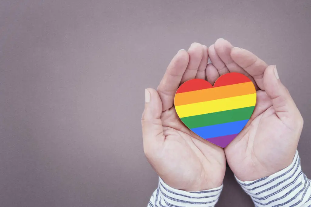 Rainbow hearts symbolize gay and LGBT pride on a human hand. Concept of human relationship, support and stay together.
