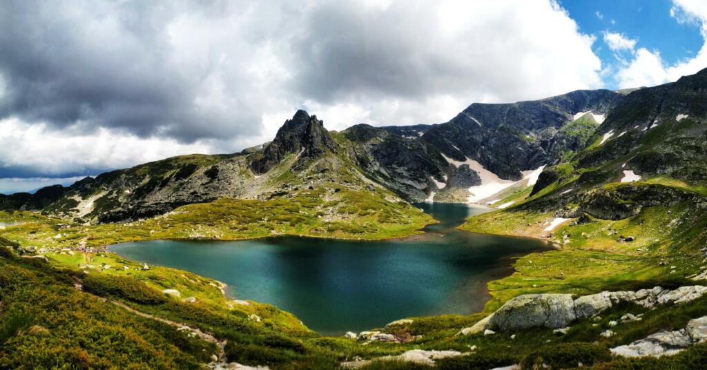 Gorsko jezero, obdaja ga trava, v ozadju so zasnežene gore