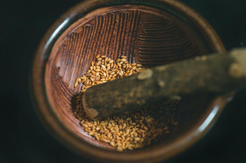 Roasted sesame seeds in a wooden grinding bowl.