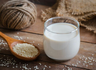 Je sezamovo mleko prihodnost mleka? Sesame milk in glass and white sesame seeds on wooden spoon