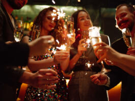 Sparkling sparklers in the hands. Playing firework to celebrate winter holidays with friends at the party. Magic New Year, Christmas.