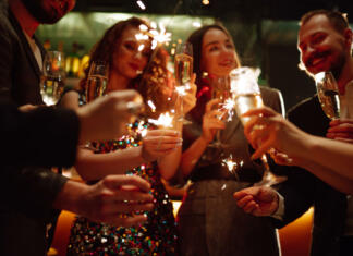 Kako silvestrovati brez alkohola? Sparkling sparklers in the hands. Playing firework to celebrate winter holidays with friends at the party. Magic New Year, Christmas.