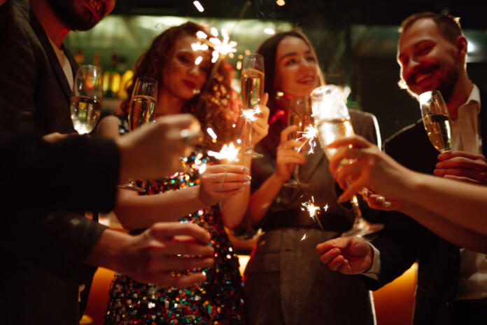 Sparkling sparklers in the hands. Playing firework to celebrate winter holidays with friends at the party. Magic New Year, Christmas.