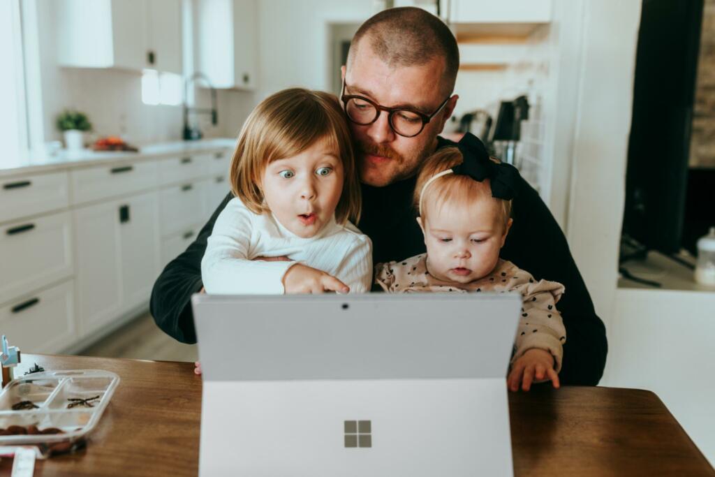 Oče, majhen otrok in malček gledajo v tablični računalnik