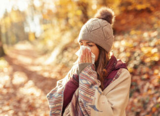 Vse, kar moraš vedeti o gripi Woman caught a cold, blowing nose while spending sunny autumn day outdoors
