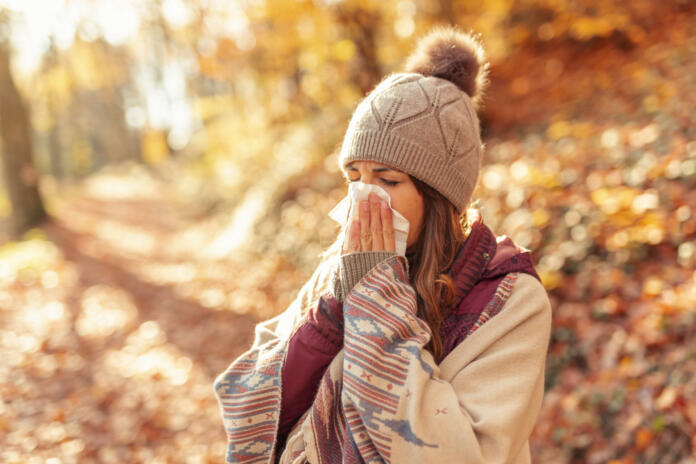 Woman caught a cold, blowing nose while spending sunny autumn day outdoors