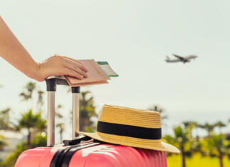 Študent priporoča: 5 knjig za popotnike založbe Morfem Roka drži kovček, na katerem je klobuk, v ozadju pristaja letalo